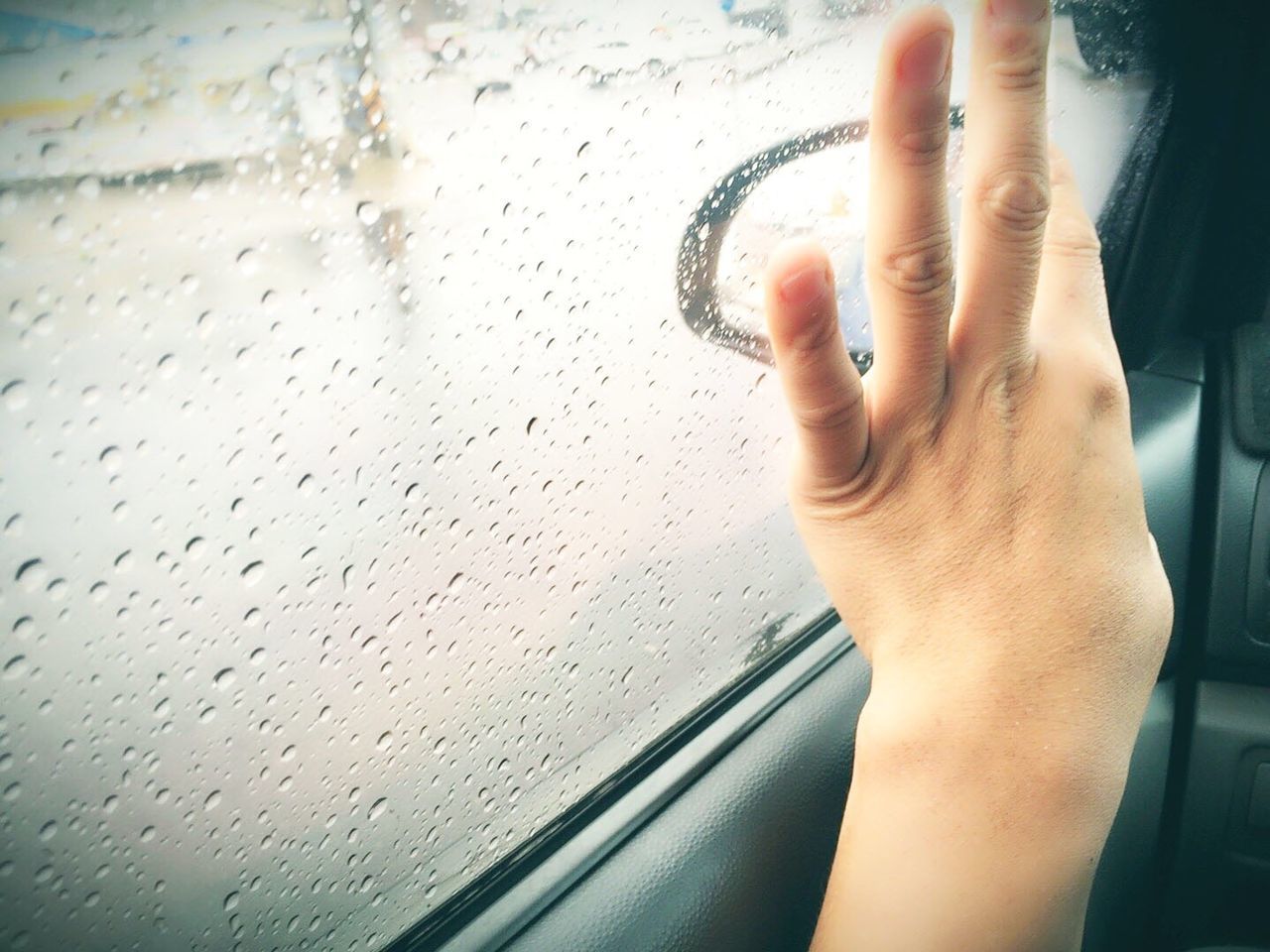 Close-up of hand touching condensed glass window