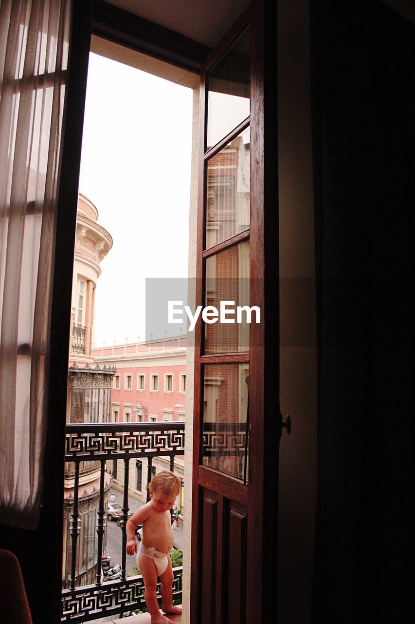 BOY LOOKING THROUGH WINDOW IN BUILDING