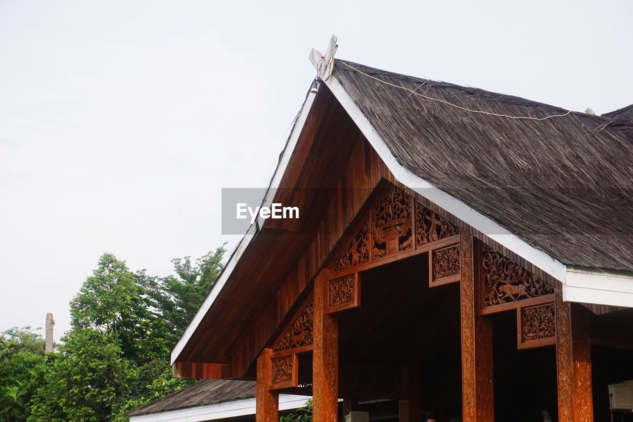 LOW ANGLE VIEW OF COTTAGE ON BUILDING AGAINST CLEAR SKY