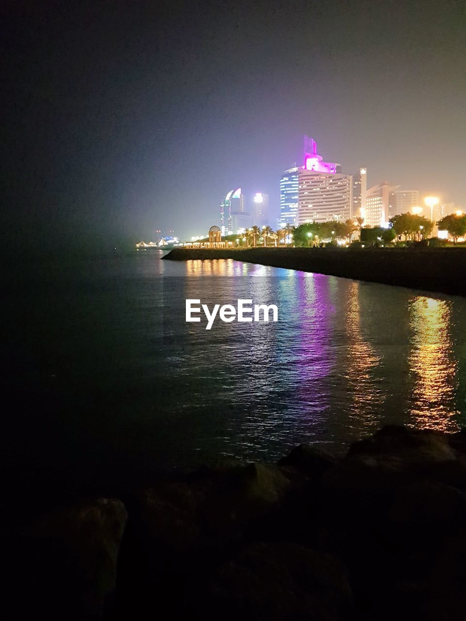 ILLUMINATED CITY BUILDINGS AT WATERFRONT