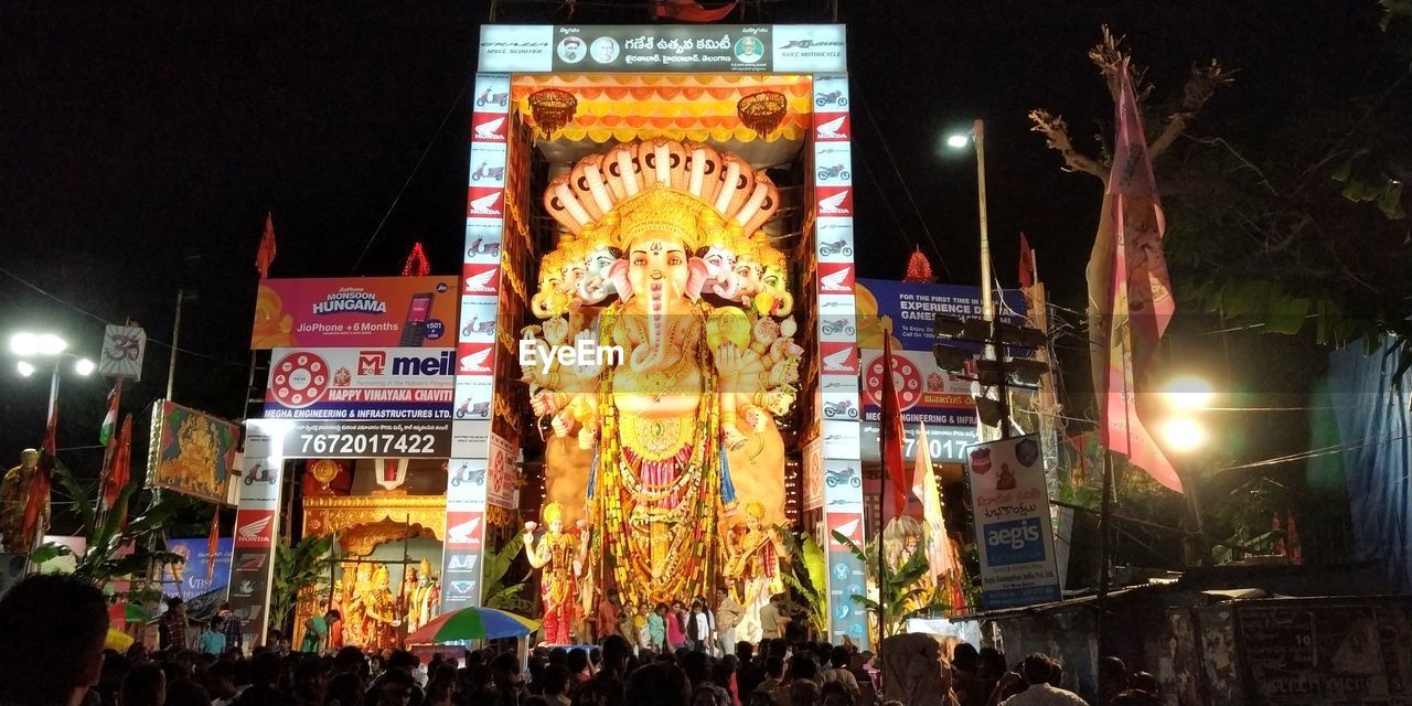 GROUP OF PEOPLE IN FRONT OF ILLUMINATED BUILDING