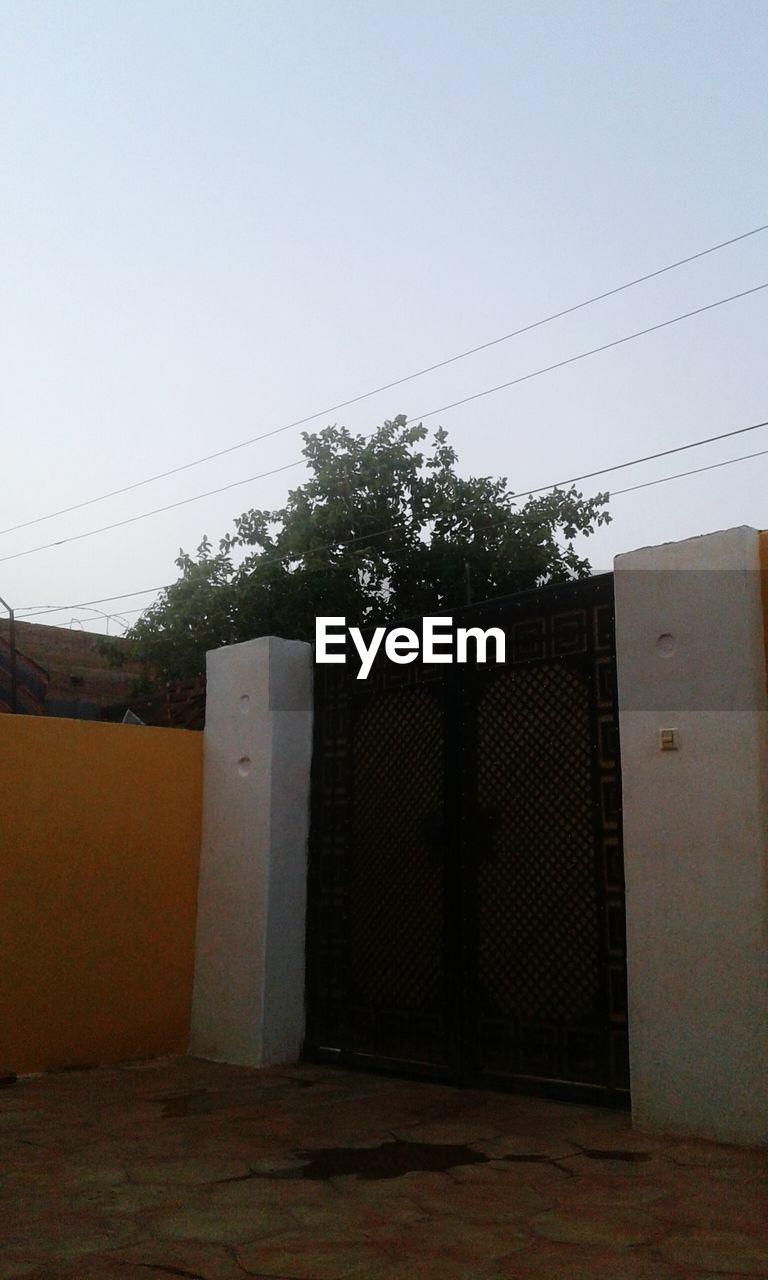 wall, sky, architecture, electricity, no people, built structure, cable, nature, building, building exterior, plant, clear sky, tree, entrance, day, technology, house, outdoors, wood