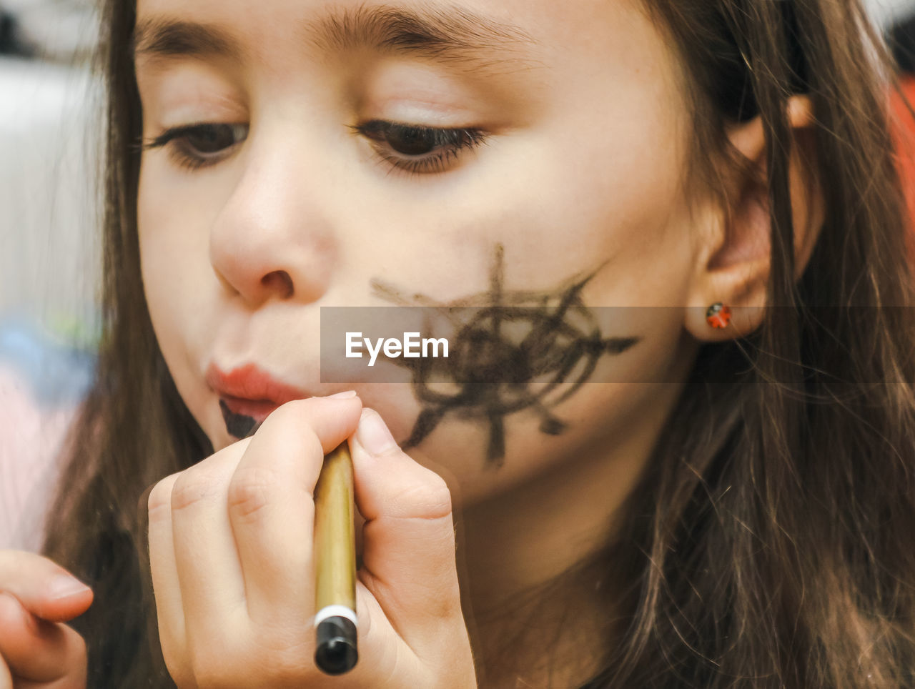 Little girl puts on halloween makeup.