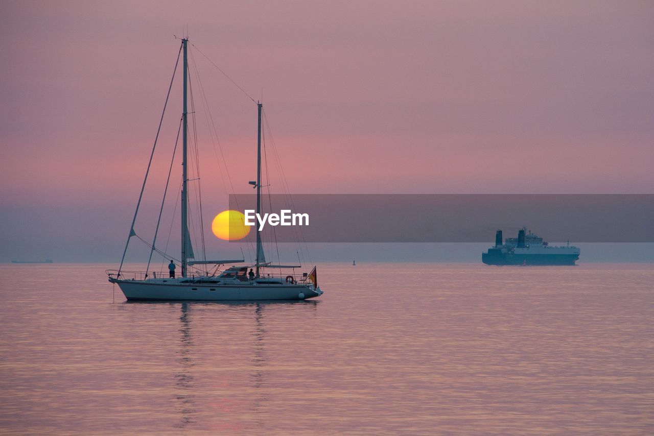 Boat on sea against sky during sunset