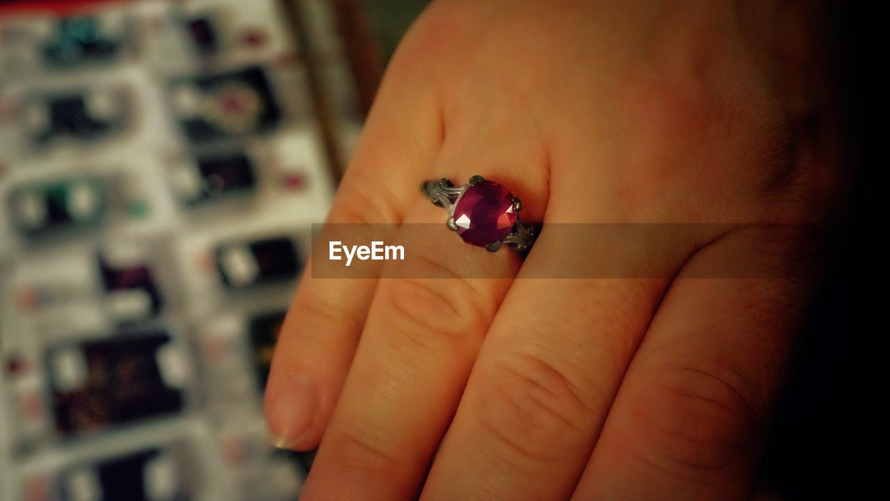Cropped image of woman with red ruby ring on finger