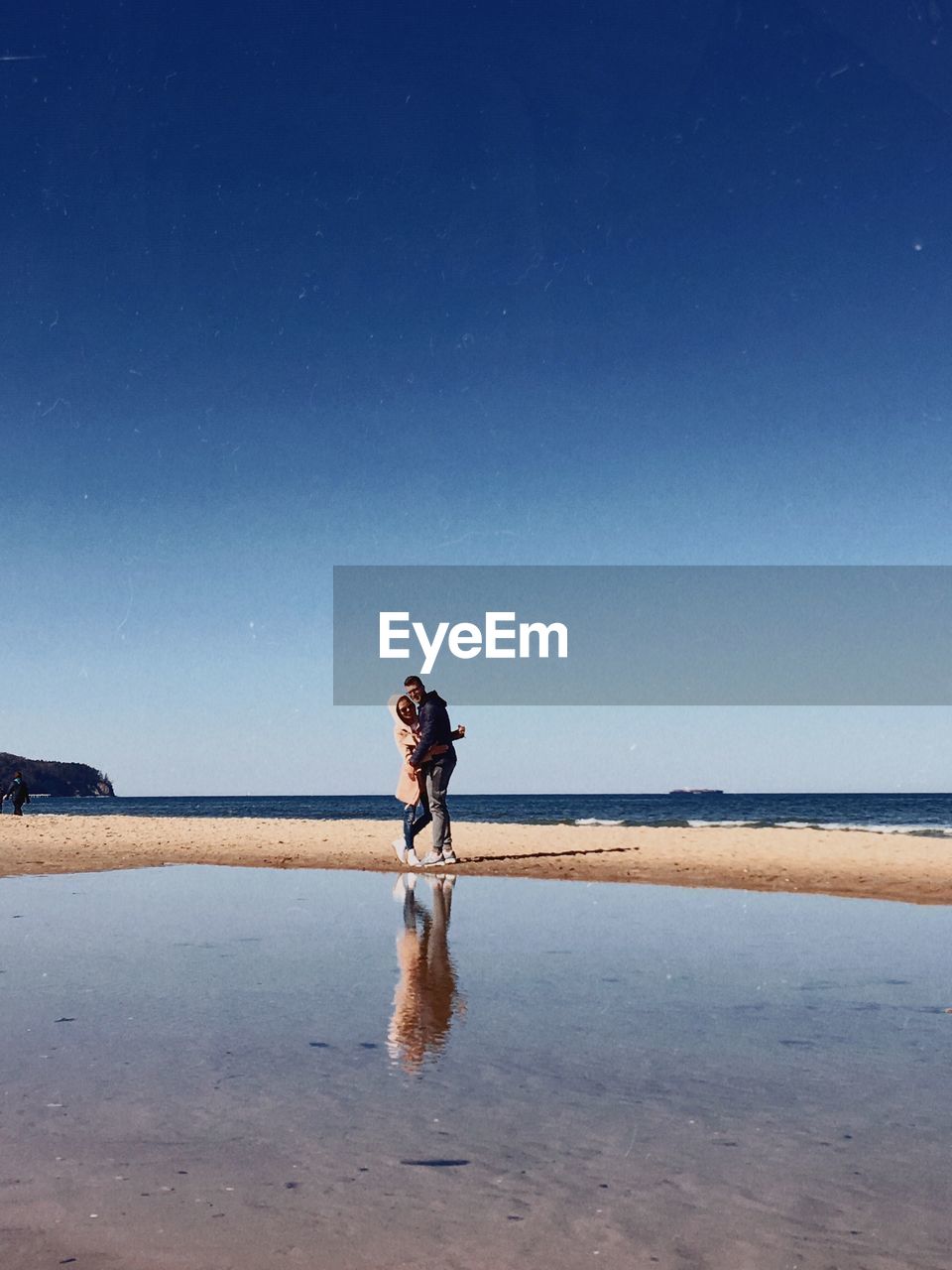 Couple standing on sea shore against blue sky at sopot