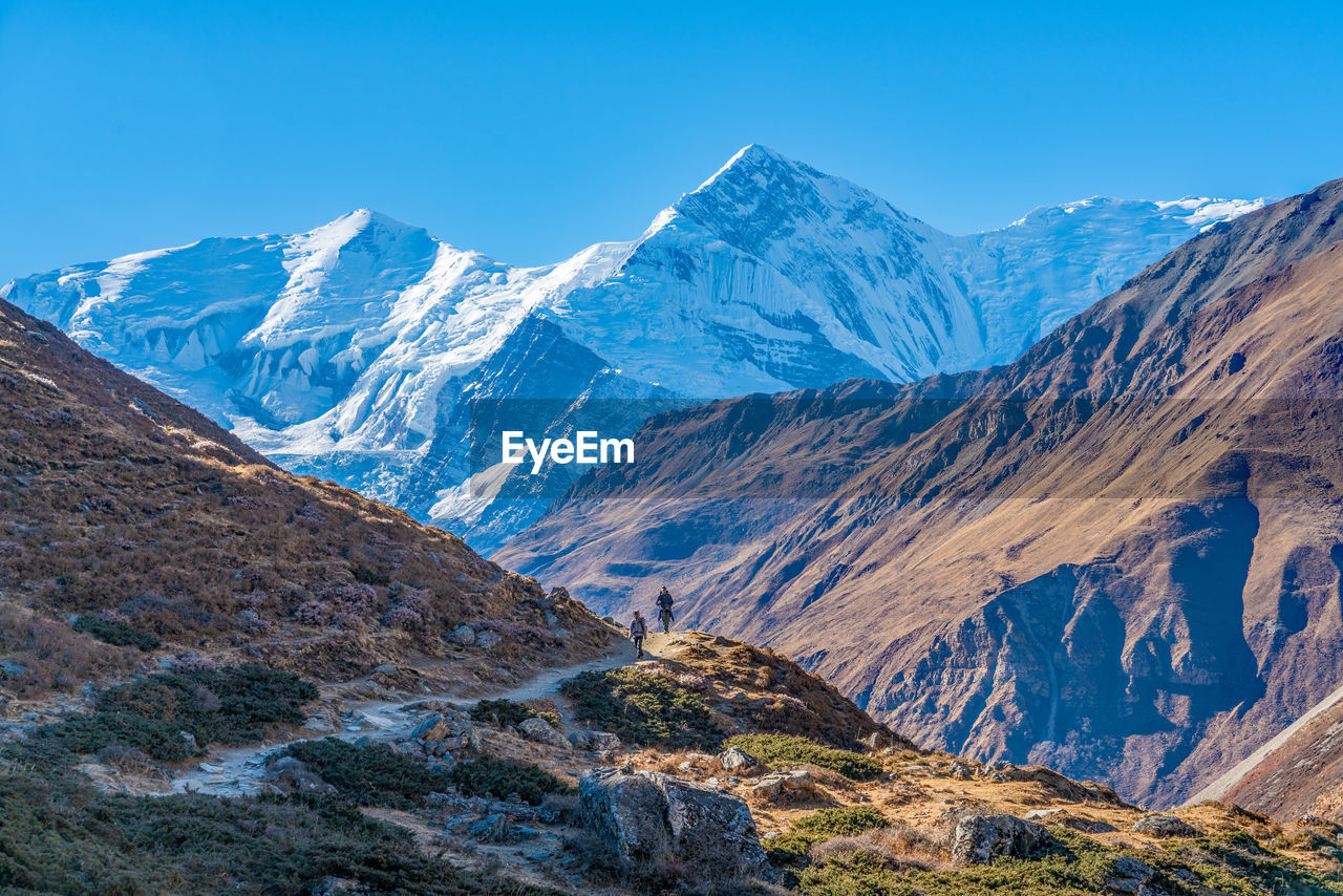 Scenic view of snowcapped mountains against blue sky