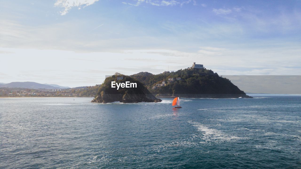 A landscape with a sailboat in the distance.