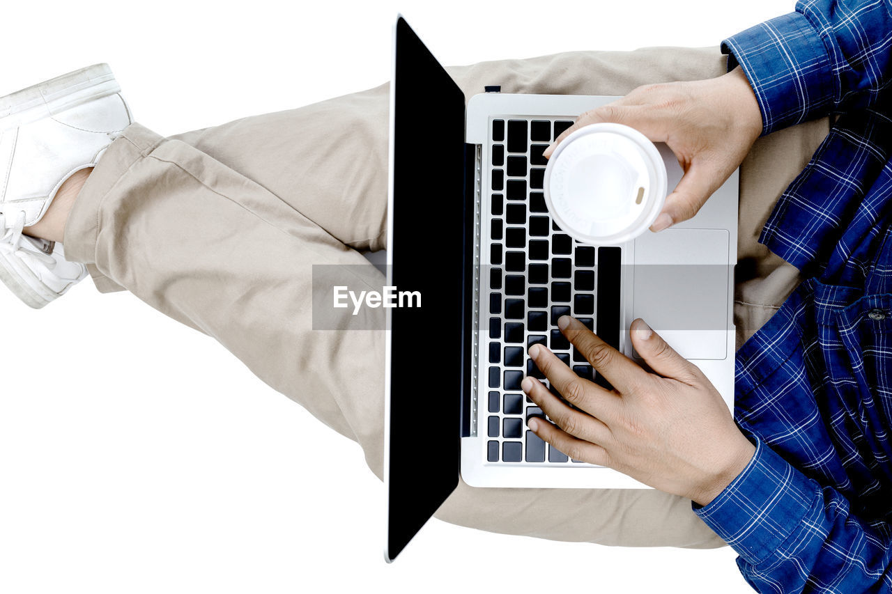 LOW ANGLE VIEW OF MAN HOLDING COFFEE