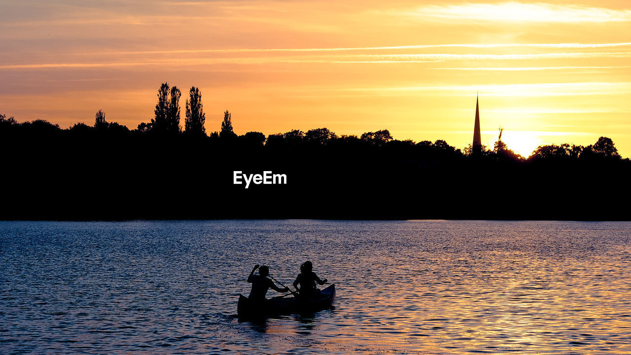 Silhouette of people kayaking on river