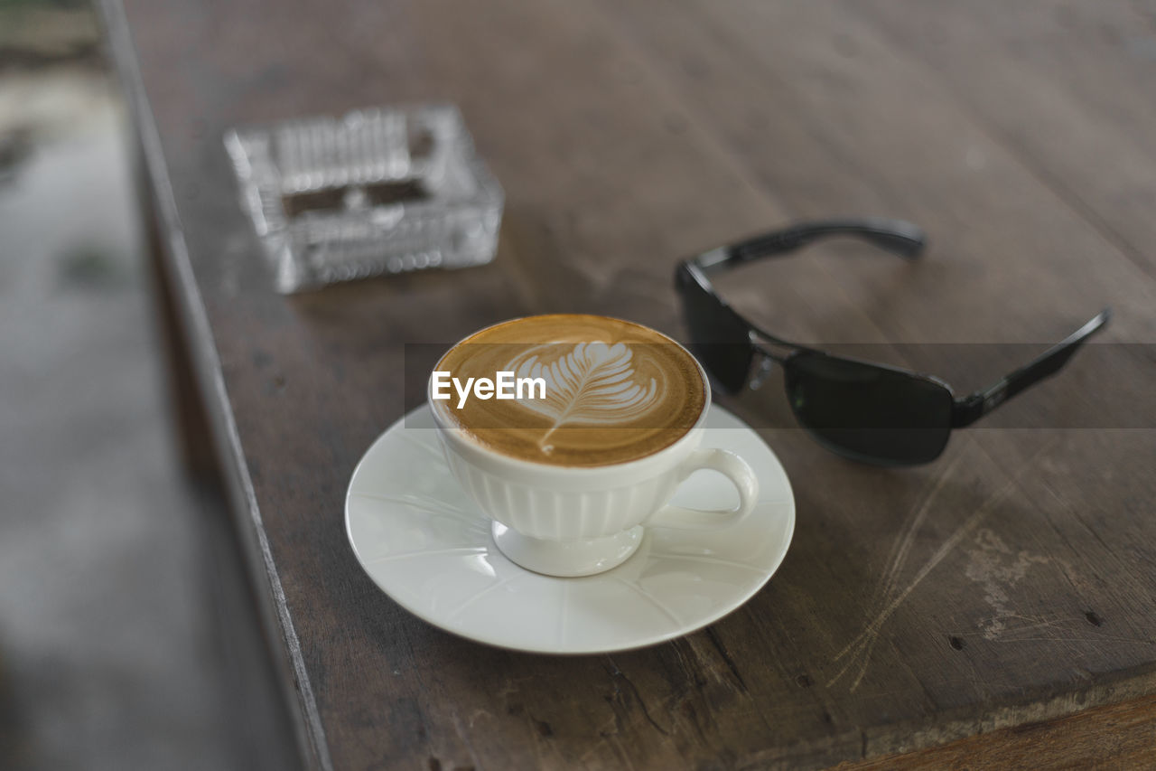 Close-up of cappuccino and sunglasses on table