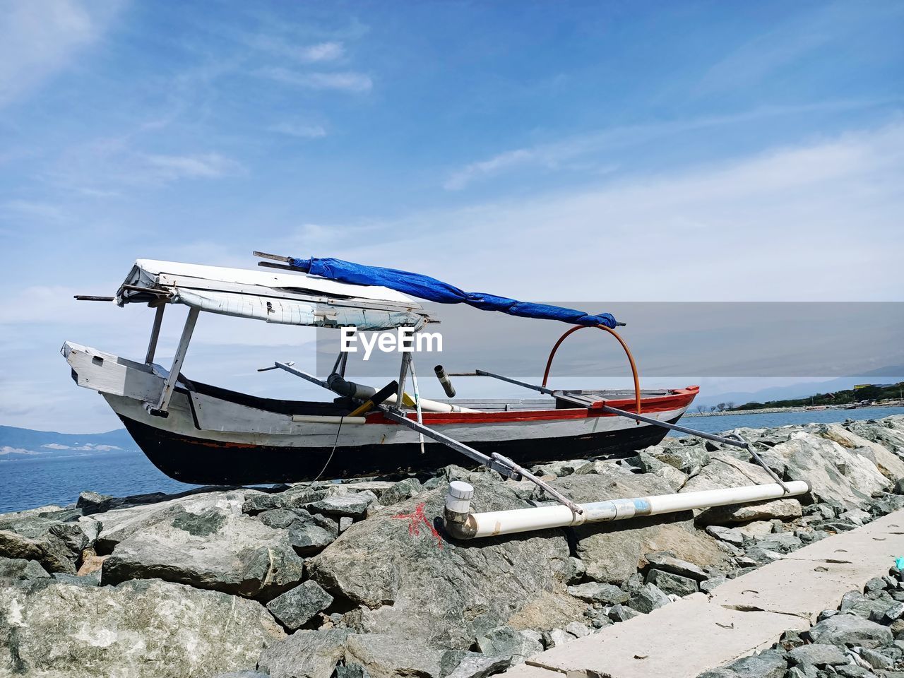 Fishing boat on beach against sky