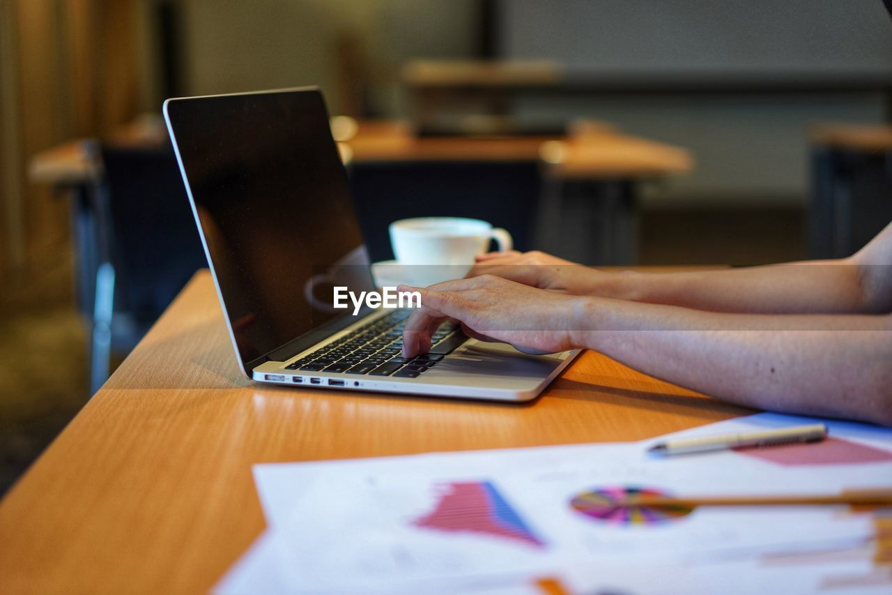 Close-up of businesswoman using laptop on table