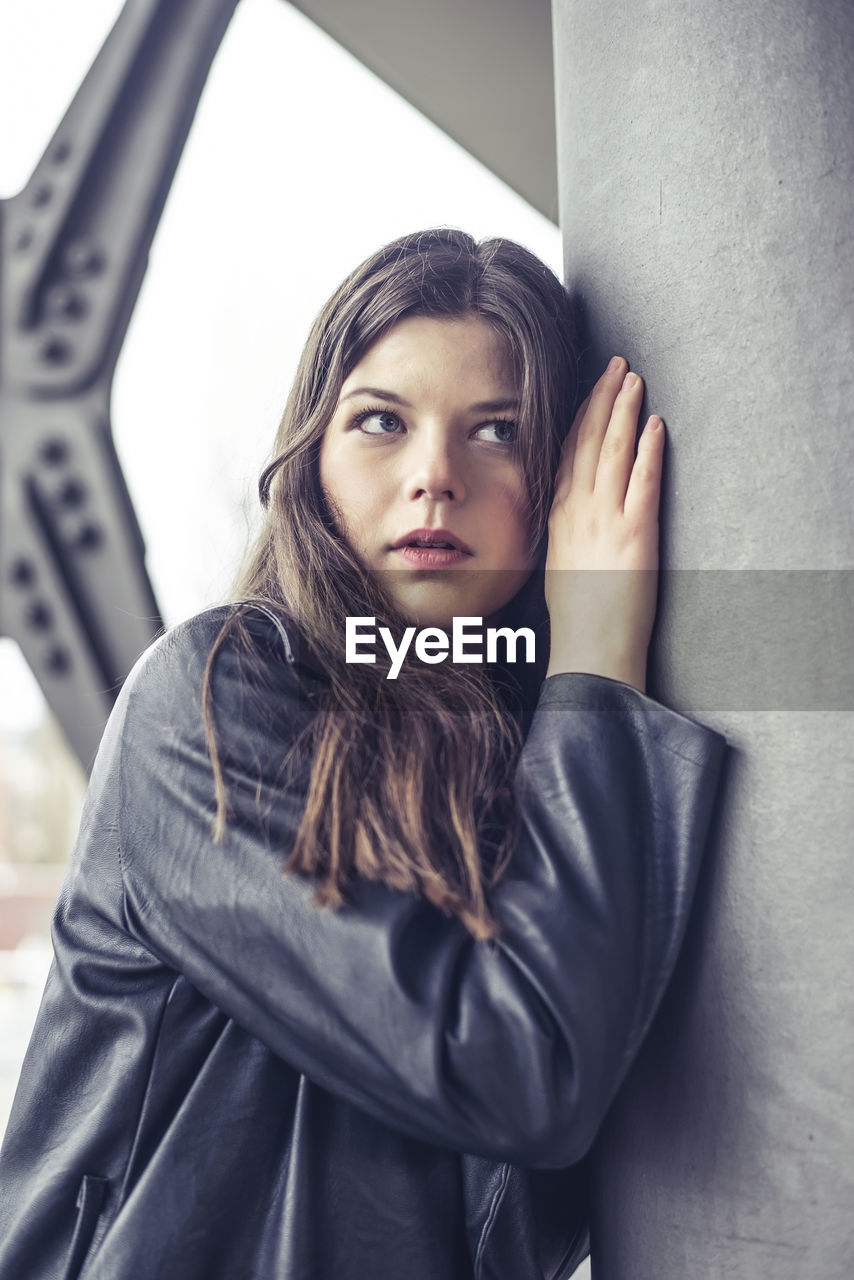 portrait of young woman standing by wall