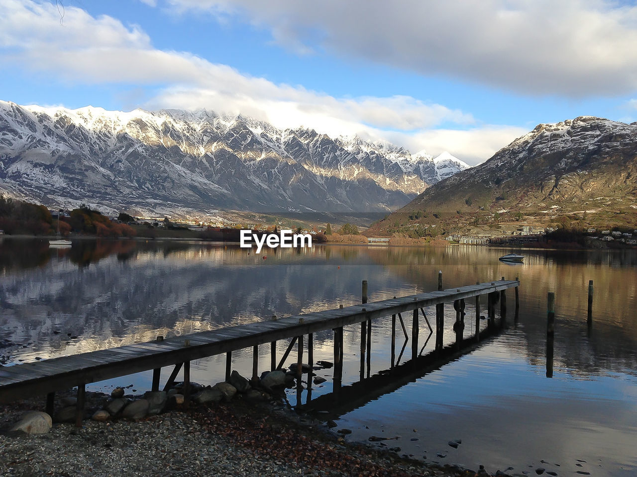 Scenic view of lake by snowcapped mountains against sky