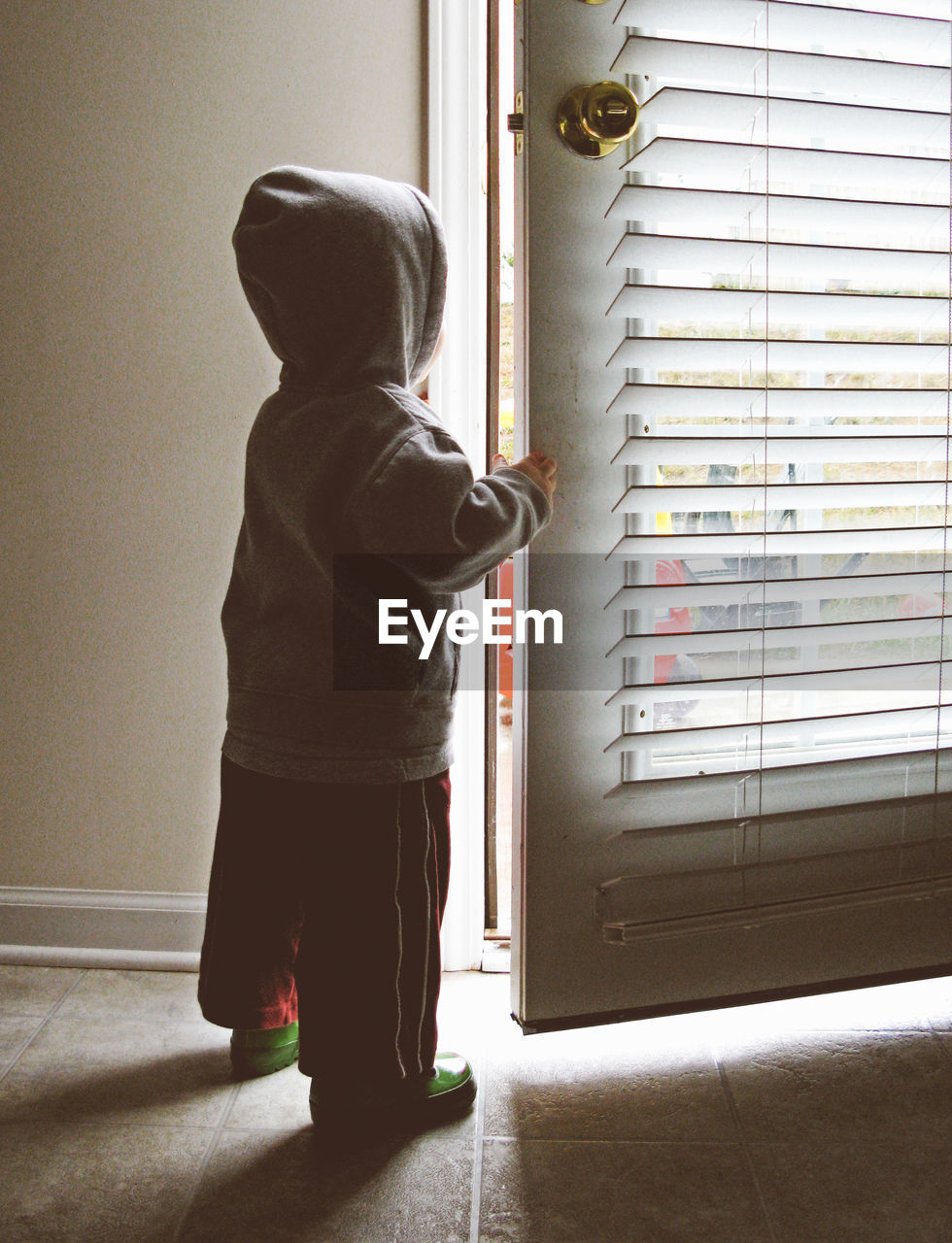 Rear view of boy looking through door at home