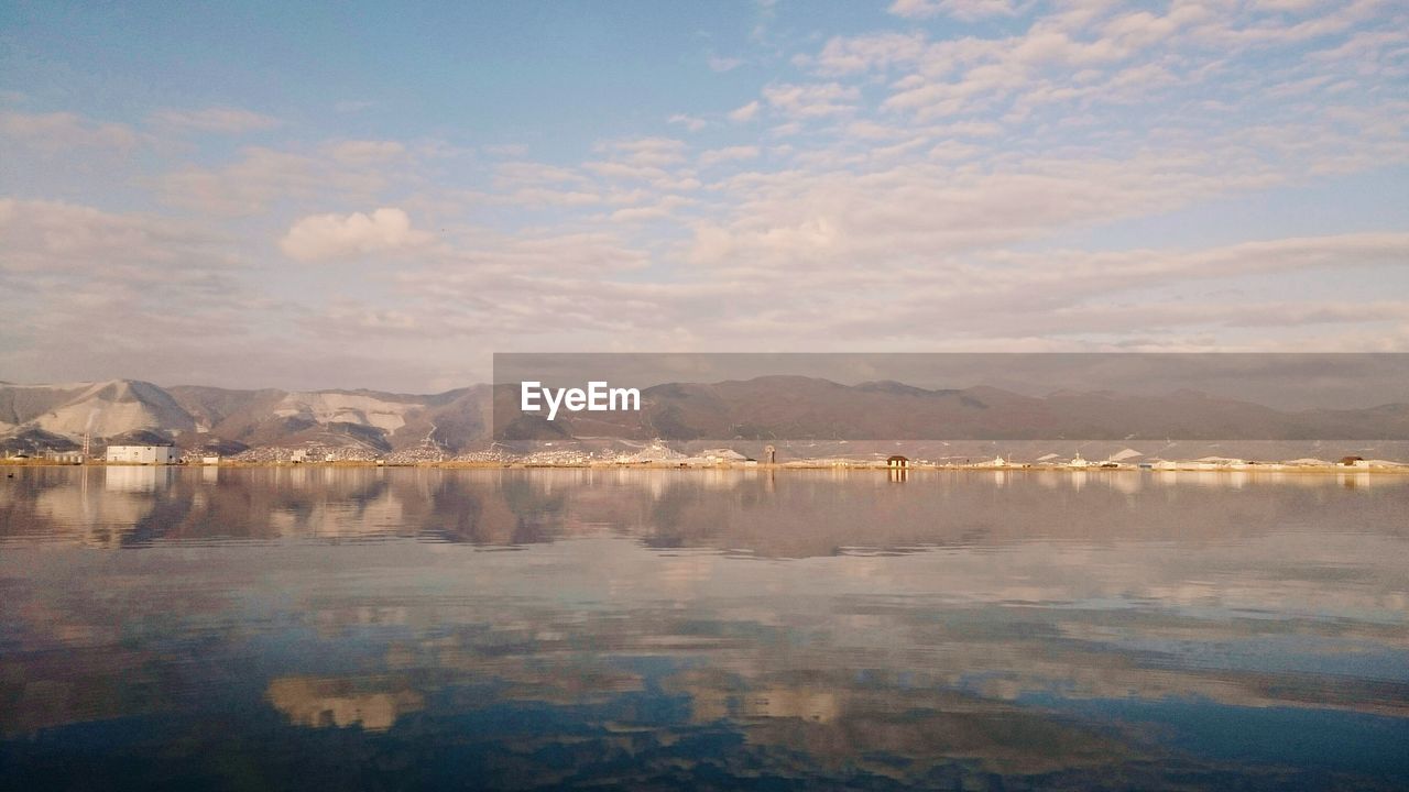 Scenic view of sea and mountains against cloudy sky