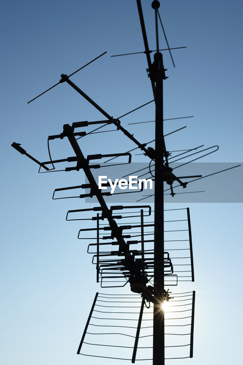 Low angle view of silhouette electricity pylon against sky