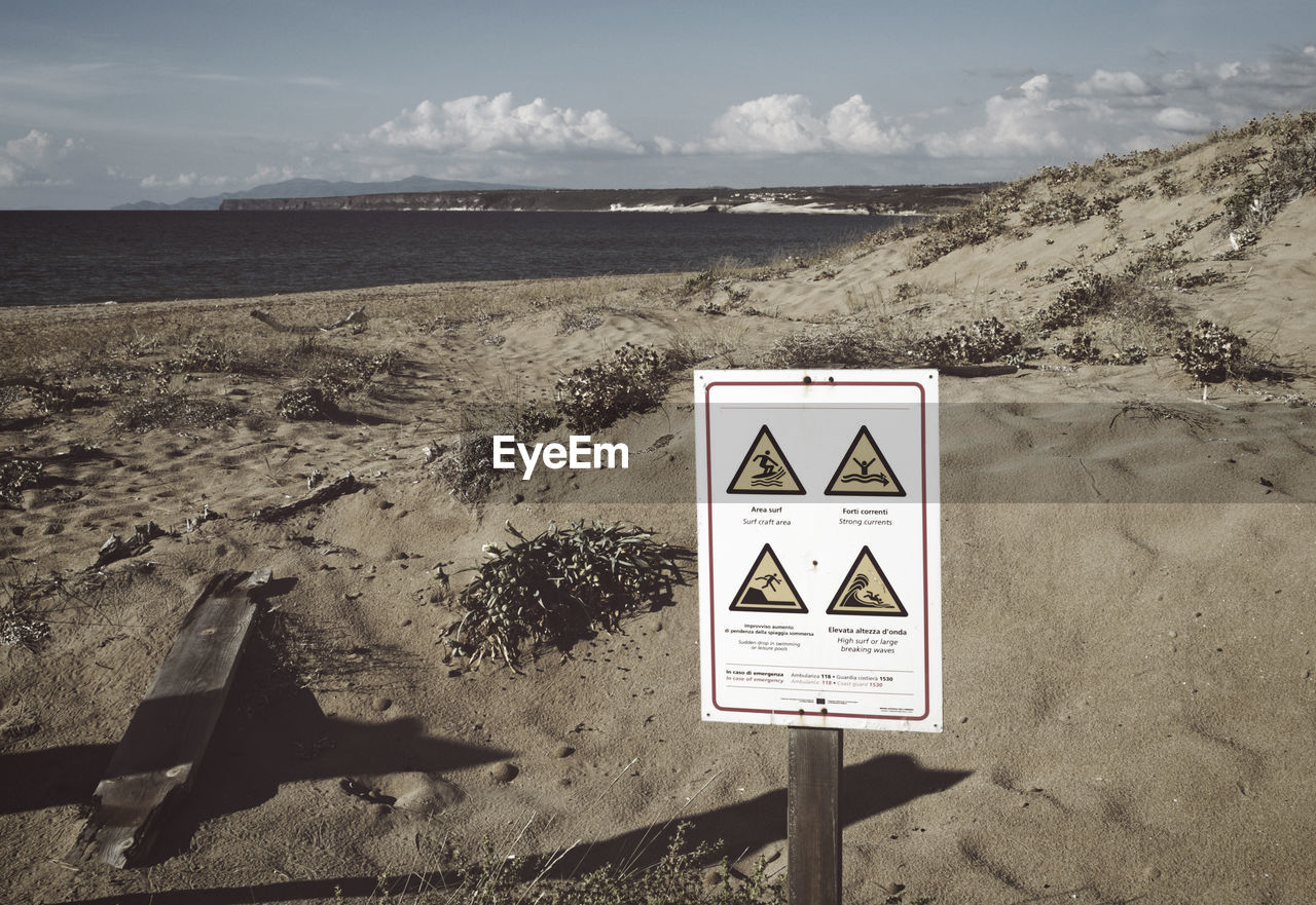 SIGN ON BEACH AGAINST SKY