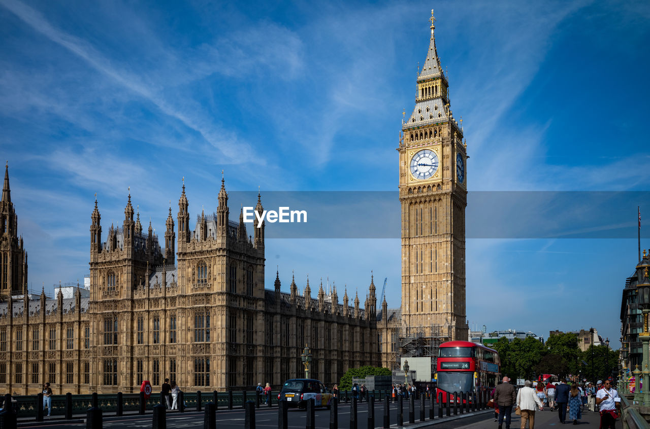 clock, architecture, clock tower, built structure, travel destinations, tower, building exterior, city, landmark, government, travel, sky, tourism, building, cityscape, nature, metropolis, time, spire, crowd, group of people, large group of people, transportation, cloud, plaza, worship, gothic style, city life, metropolitan area, street, history, politics and government, the past, outdoors, mode of transportation, parliament, town square, blue, bus, downtown, tourist, walking, urban area