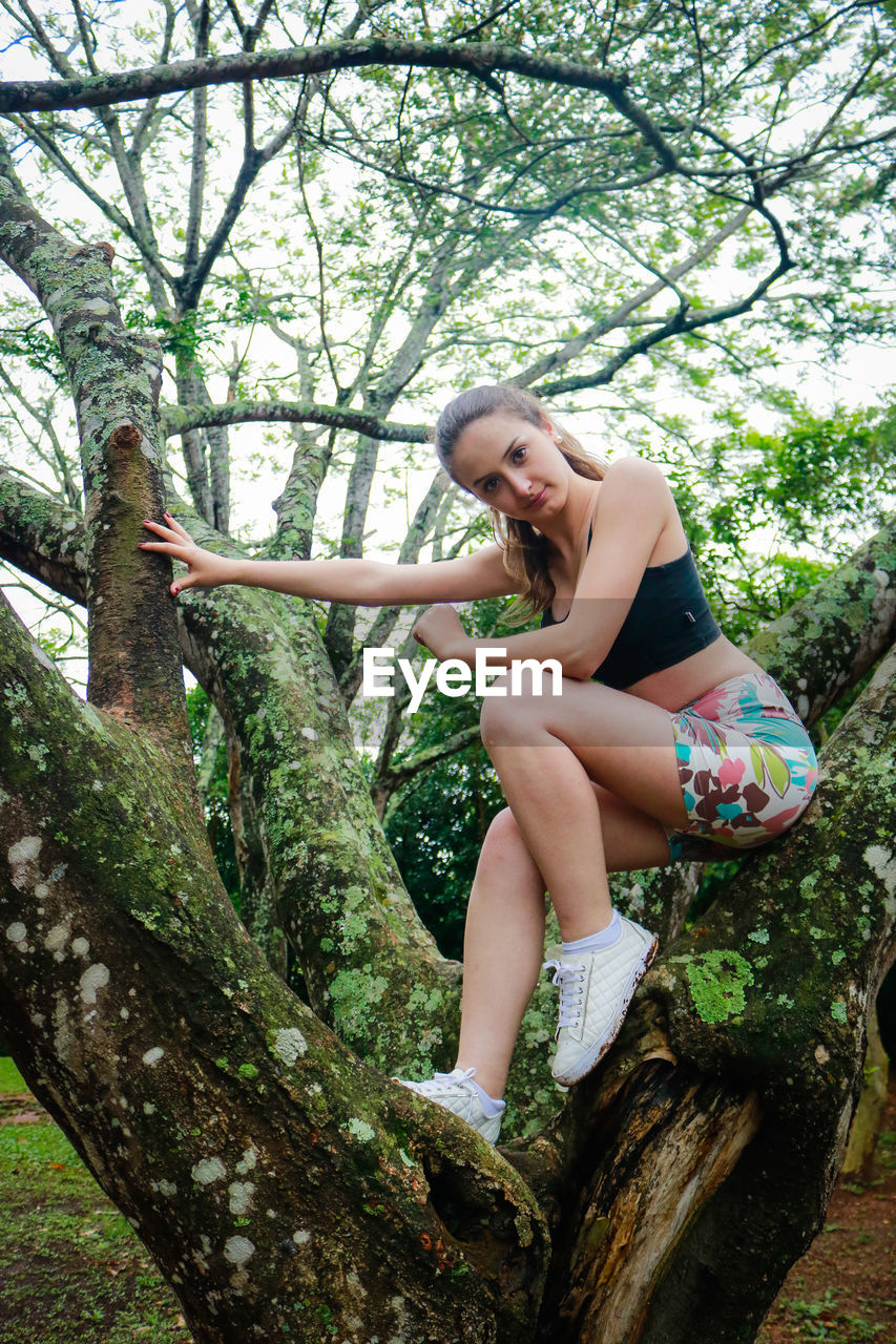 Low angle view of young woman on tree