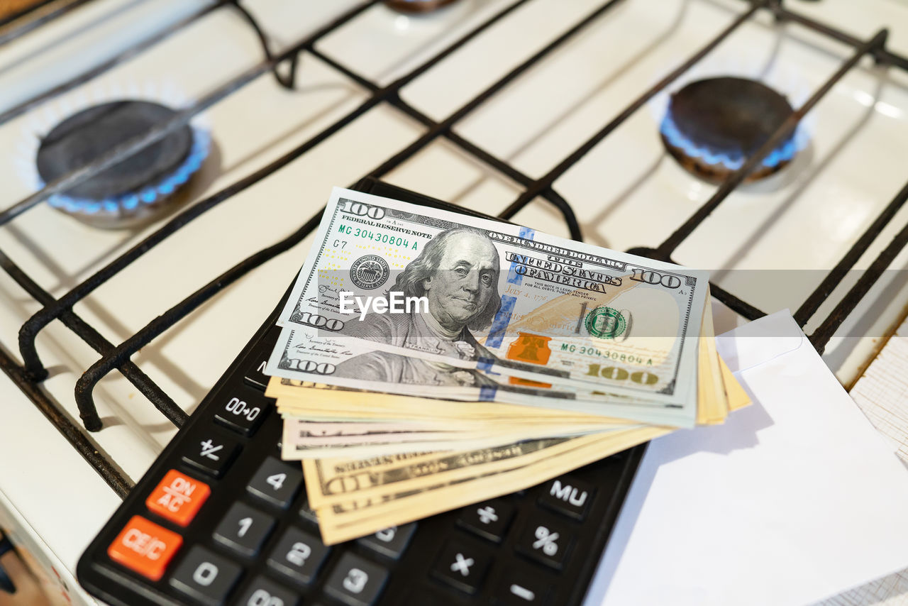 Banknotes lie next to a burning gas burner along with a calculator.