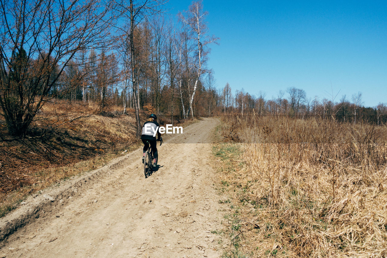 Full length of woman riding bicycle in forest