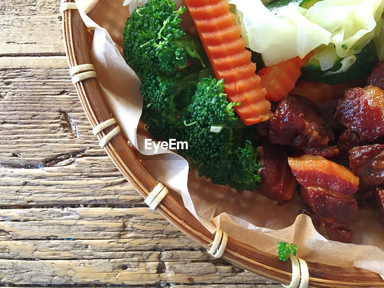 Close-up of pork belly with vegetables in wicker container on table