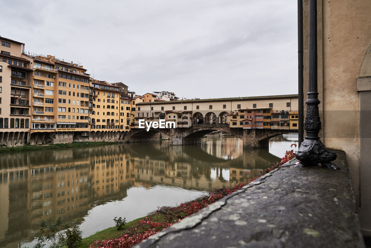 Bridge over canal by buildings against sky