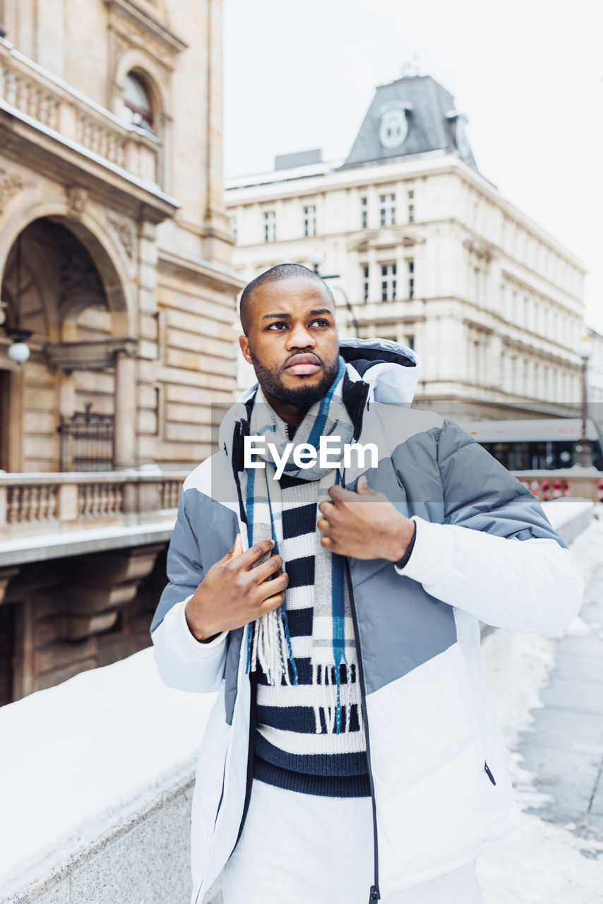 Young african man on street, snow winter season, city portrait