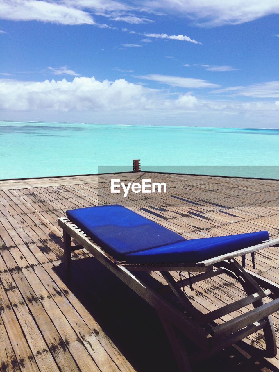 CHAIRS AND TABLE BY SWIMMING POOL AGAINST SEA