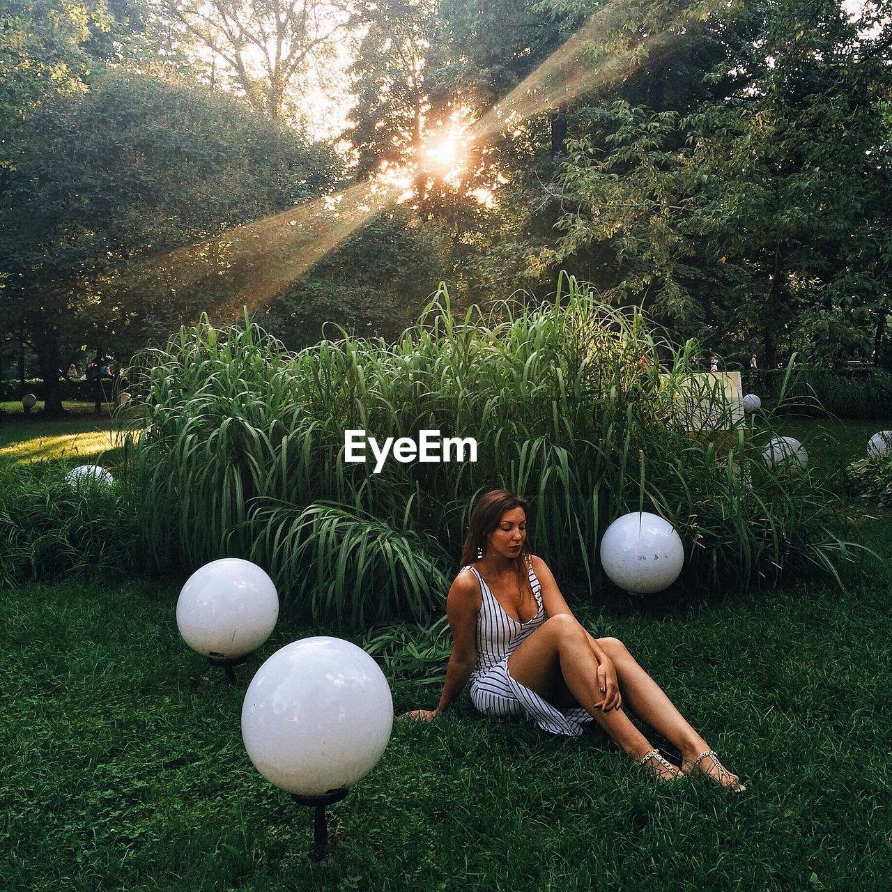 High angle view of seductive woman sitting on grassy field during sunny day at park