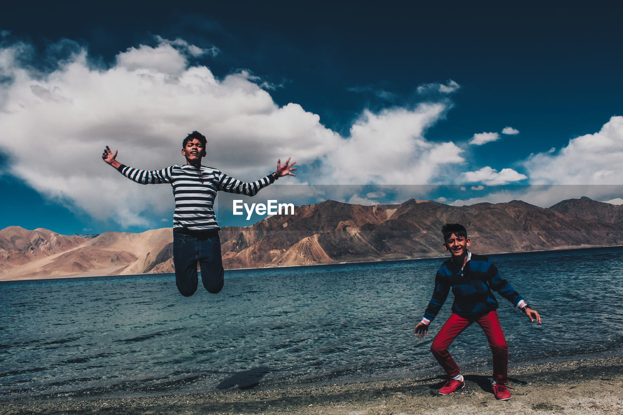 FULL LENGTH OF MAN WITH ARMS OUTSTRETCHED AGAINST SKY