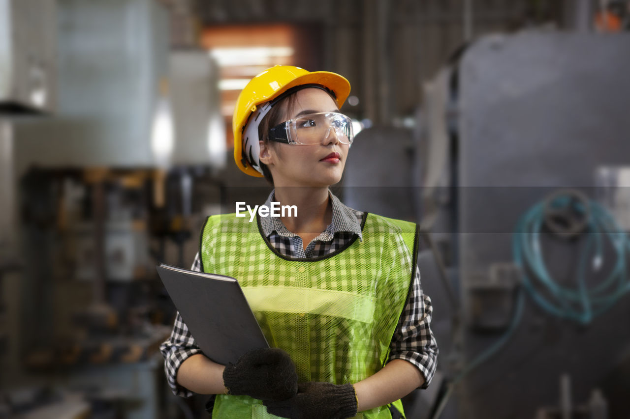 MID ADULT WOMAN WORKING IN FRONT OF MACHINE