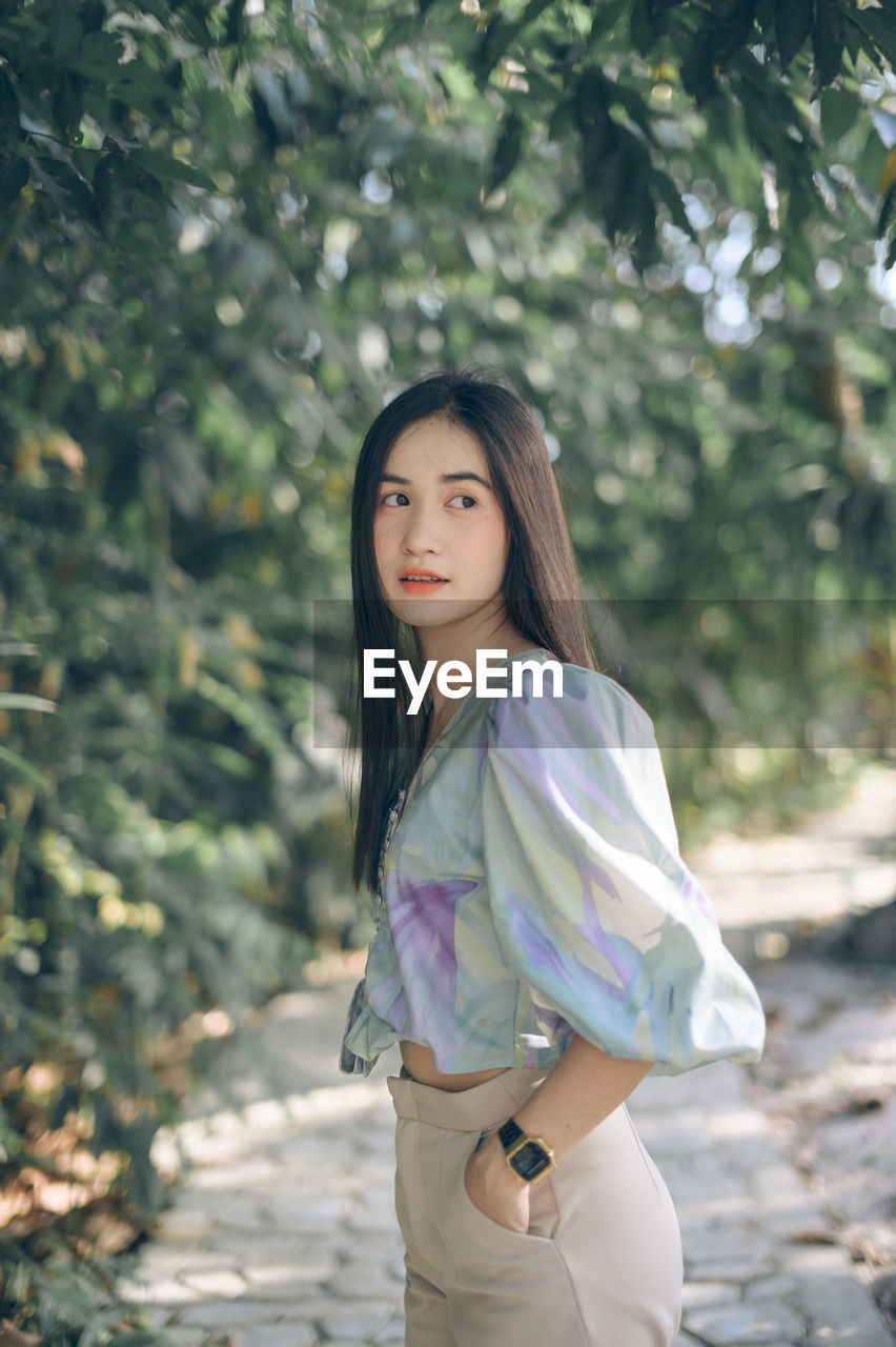 Beautiful young woman looking away while standing in park