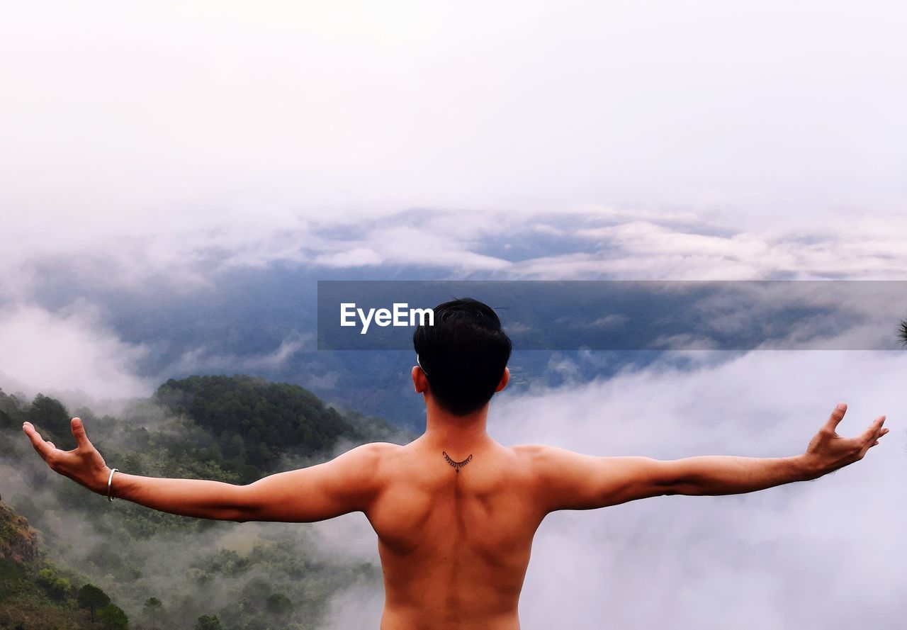 Rear view of shirtless man standing against sky