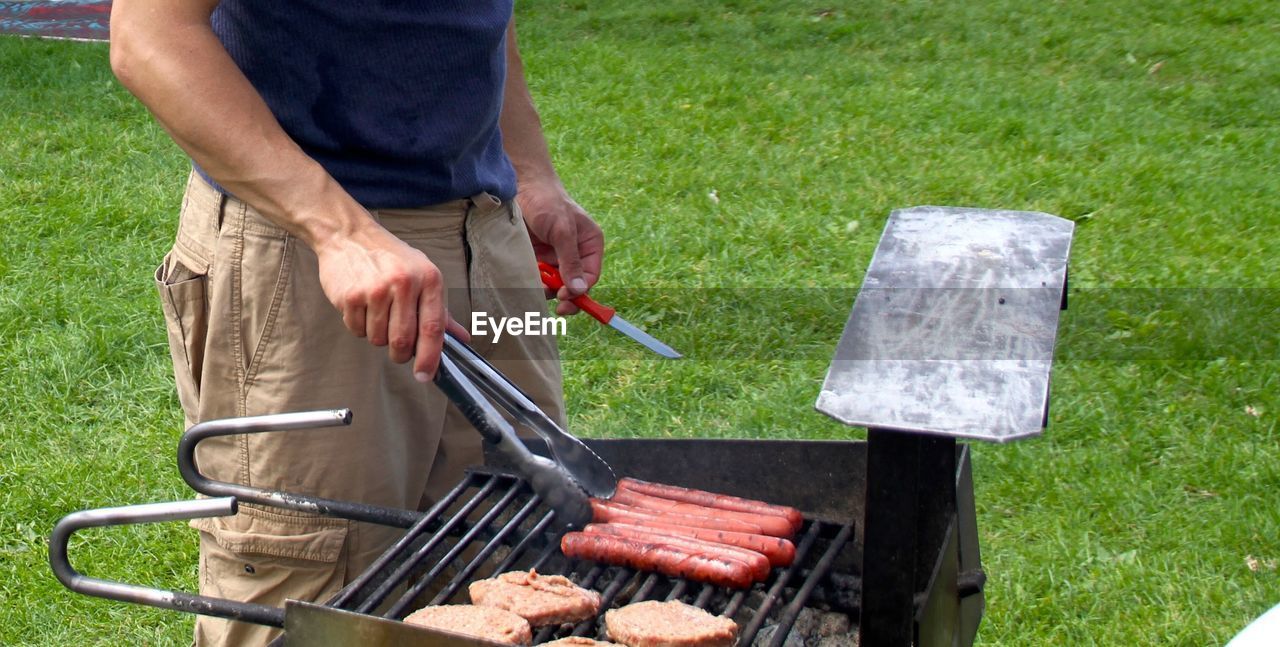 MIDSECTION OF MAN HOLDING BARBECUE GRILL