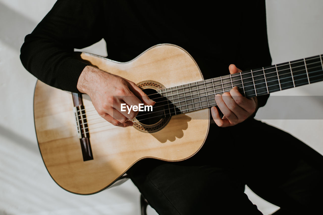 Midsection of man playing classical guitar