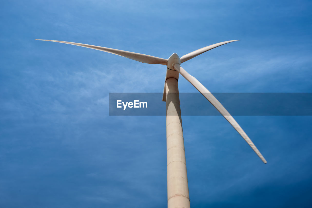 Low angle view of wind turbine against blue sky