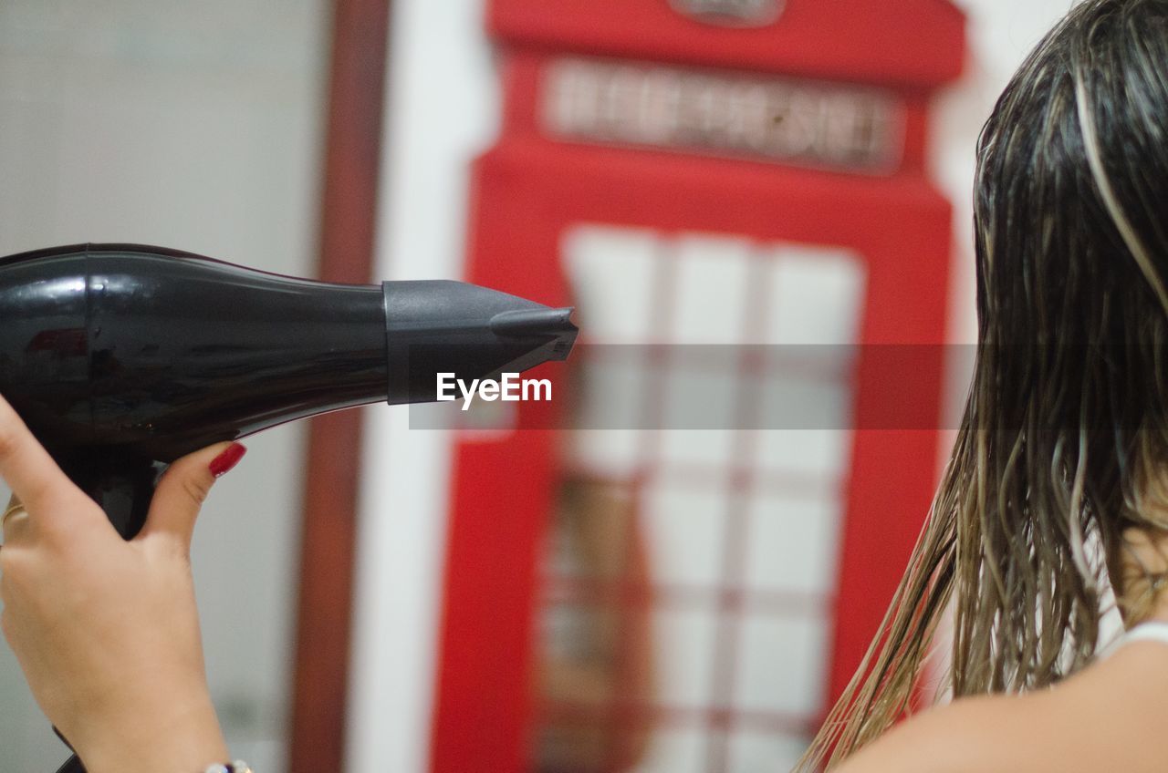 Close-up of woman drying hair with dryer