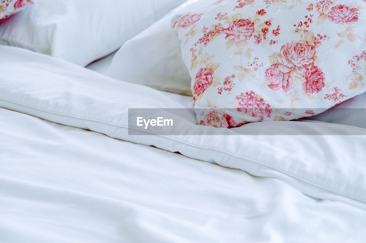 Bright bedroom interior with flower pattern pillows on bed 