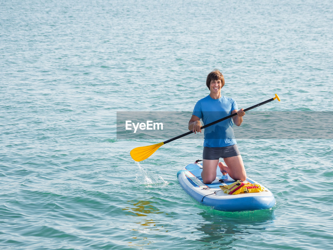 Handsome sportsman on knees paddling on stand up paddleboard. sup surfing. active lifestyle. 