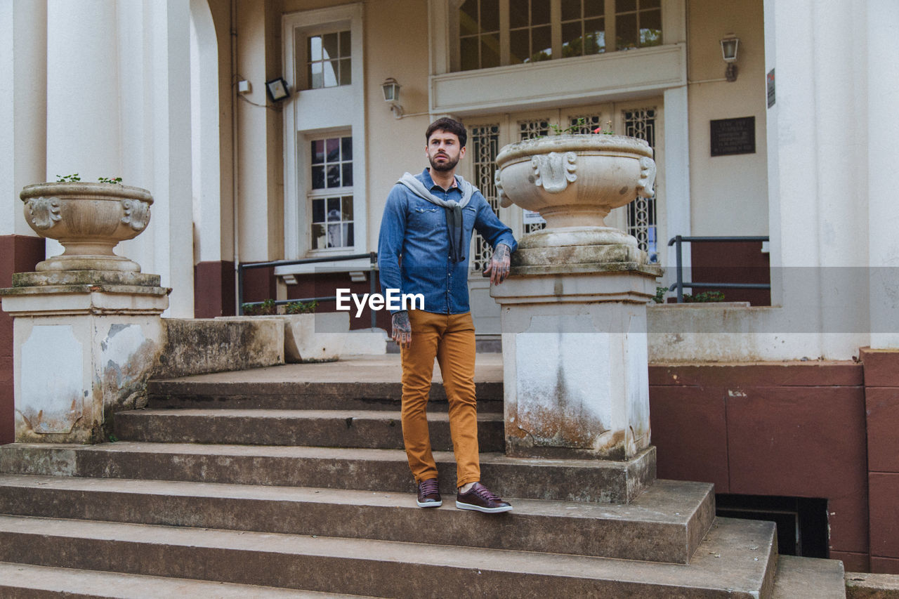 Full length of young man standing on staircase against building