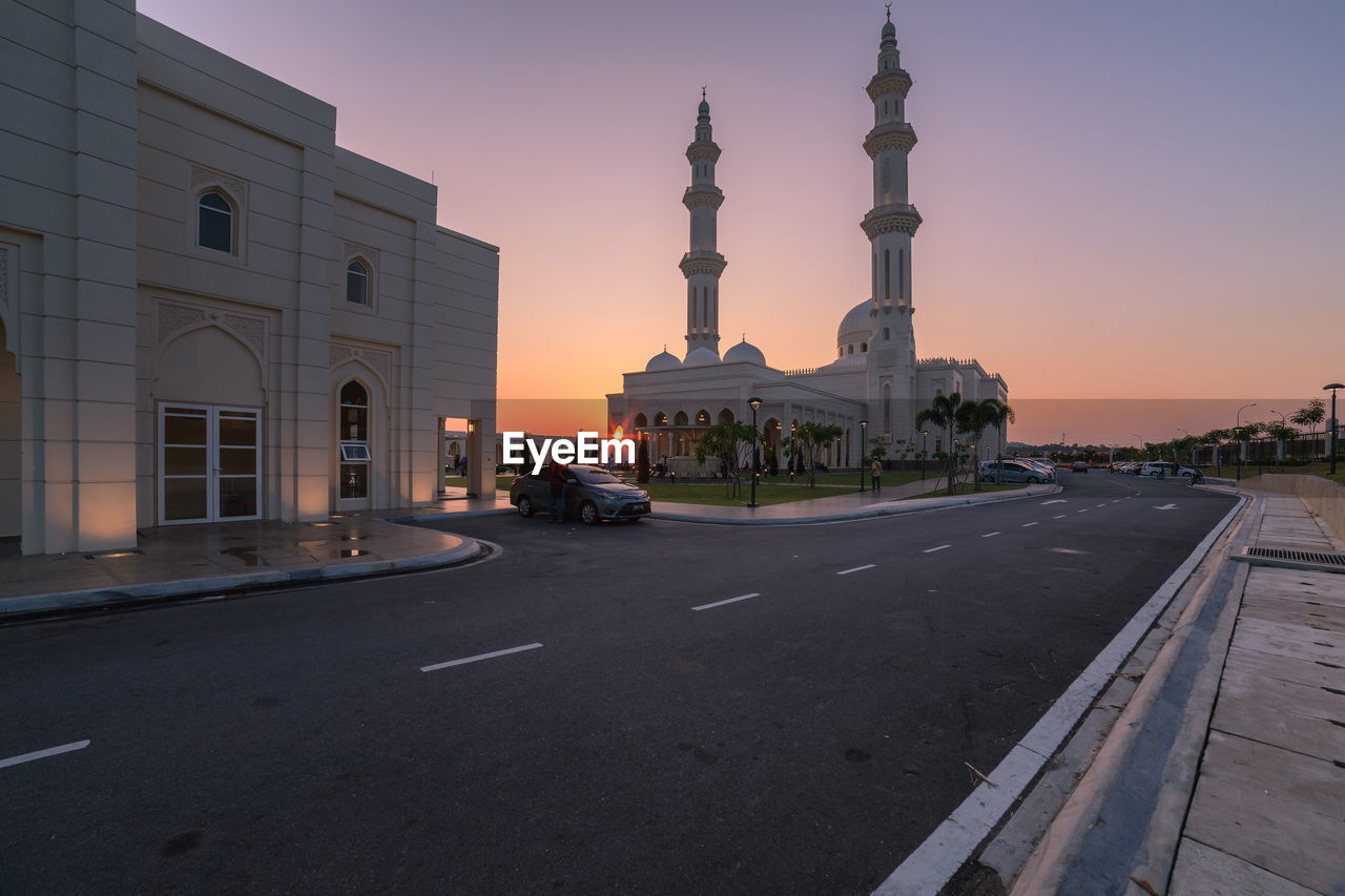 CARS ON ROAD BY BUILDINGS AGAINST SKY