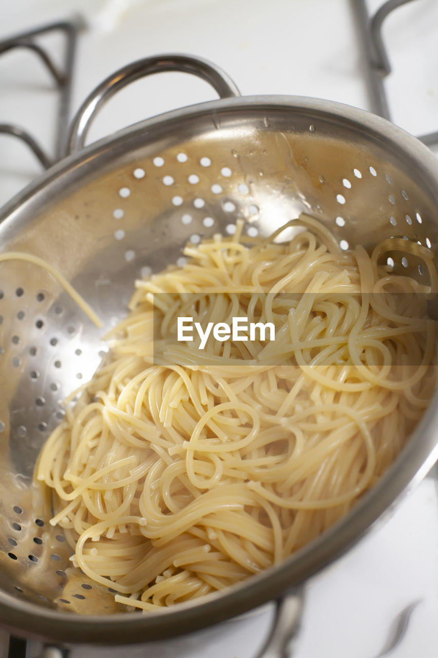 Draining hot, cooked spaghetti noodles in a colander