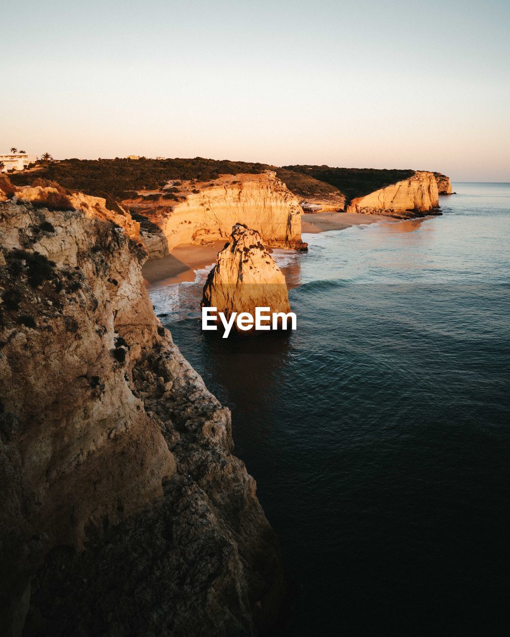 Rock formations by sea against clear sky