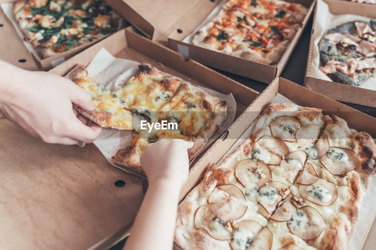 HIGH ANGLE VIEW OF PERSON HAND HOLDING PIZZA