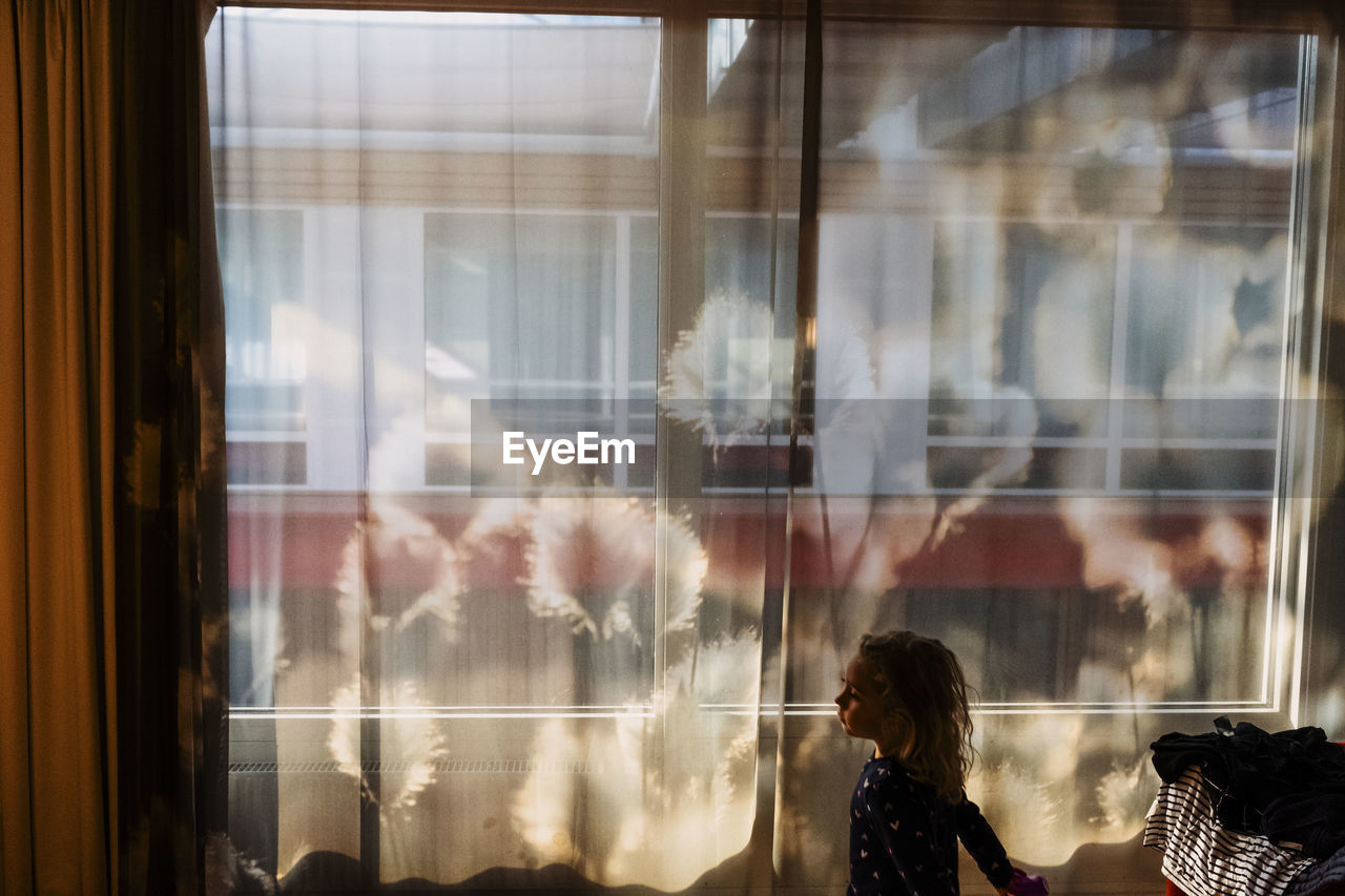 Profile of  young woman standing in front of big window