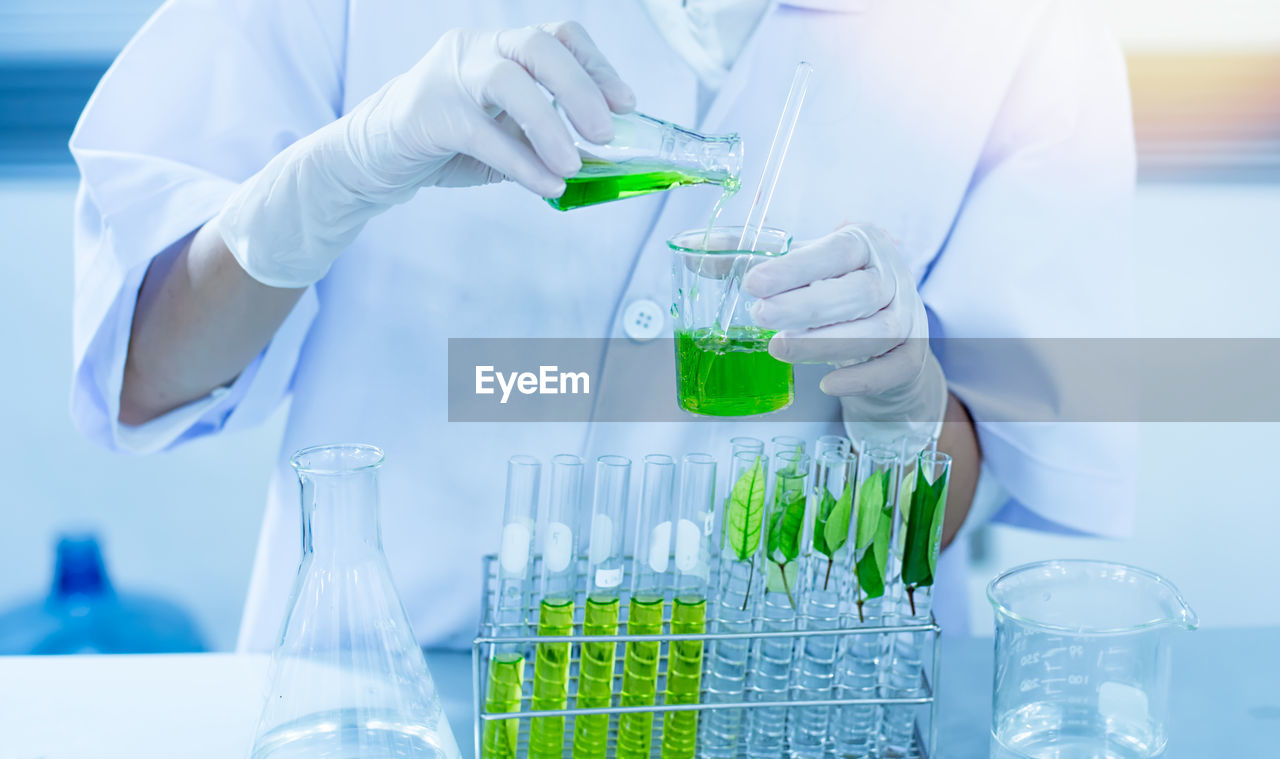 Midsection of scientist examining chemical in laboratory