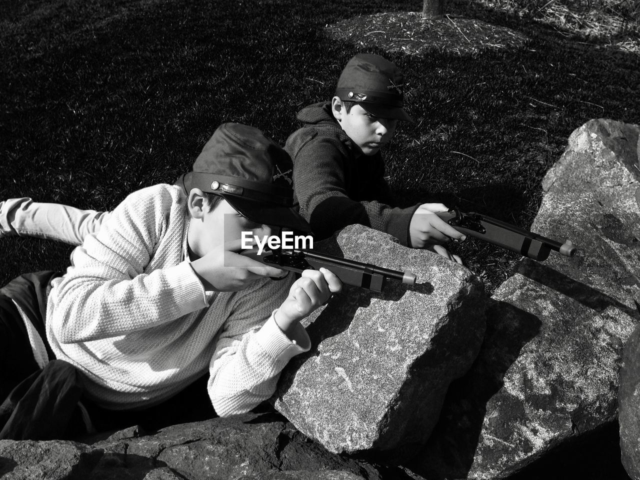 Boys shooting with toy handguns on rocks